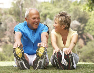 Senior Couple Exercising and Stretching In Park