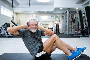 Senior man doing abdominal crunches in gym